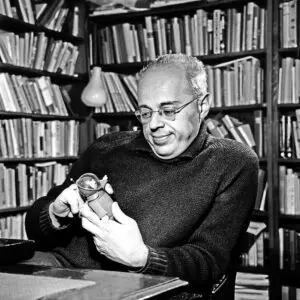 A man sitting at a table in front of shelves filled with books.