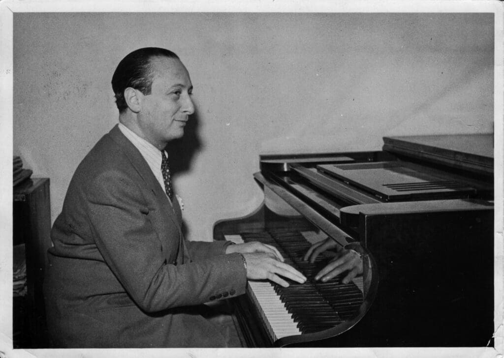 A man in suit and tie playing piano.